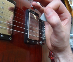 photo of fret hand rested on guitar bridge