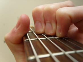 close up of thumb muting the low E string