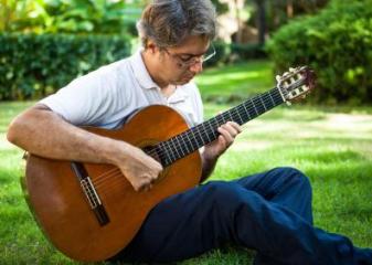 holding a guitar whilst sat on the ground